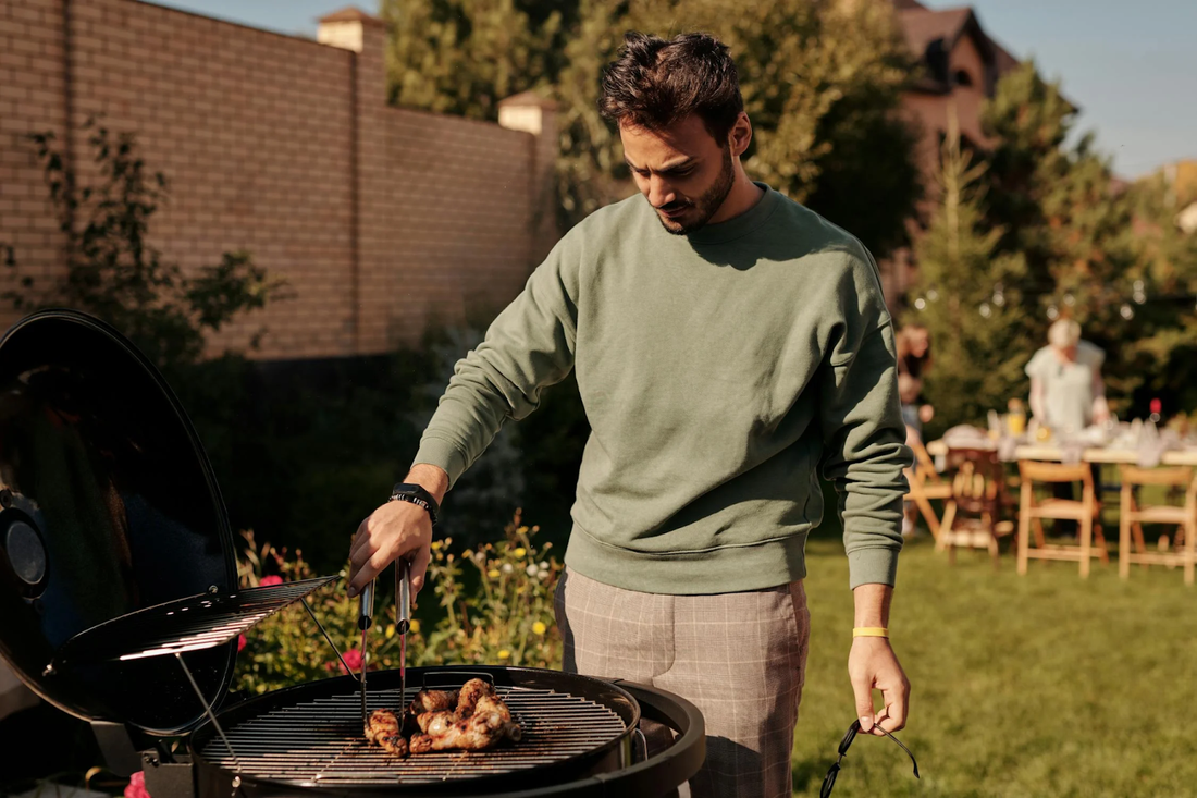 Man in backyard BBQ'ing some meat on a grill