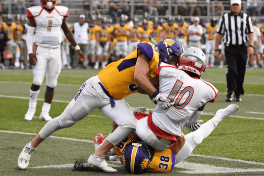 Image of two football players tackling each other and a third on the ground