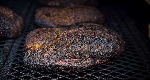 Two briskets being cooking in a smoker at truth bbq