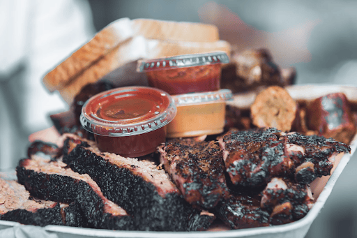 Large platter of brisket with sauces and dips on top of it