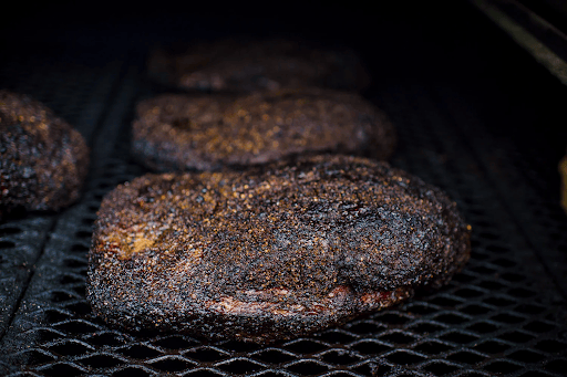 large briskets sit on the grill, almost ready to serve